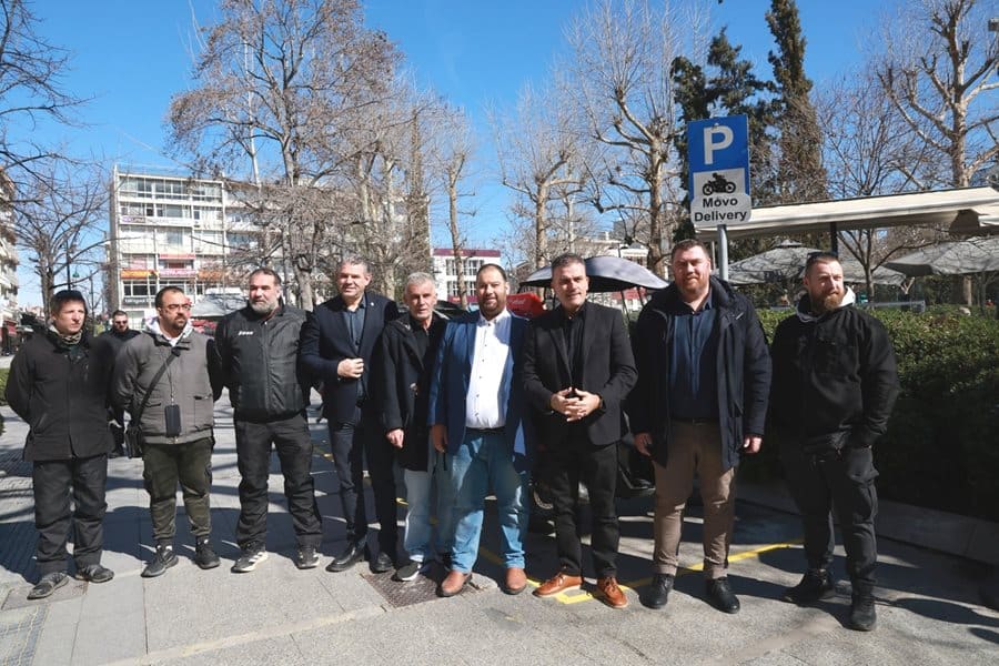 Ανθρώπινη ομάδα μπροστά από σημείο στάθμευσης μοτοσυκλετών διανομέων στο κέντρο της Λάρισας.