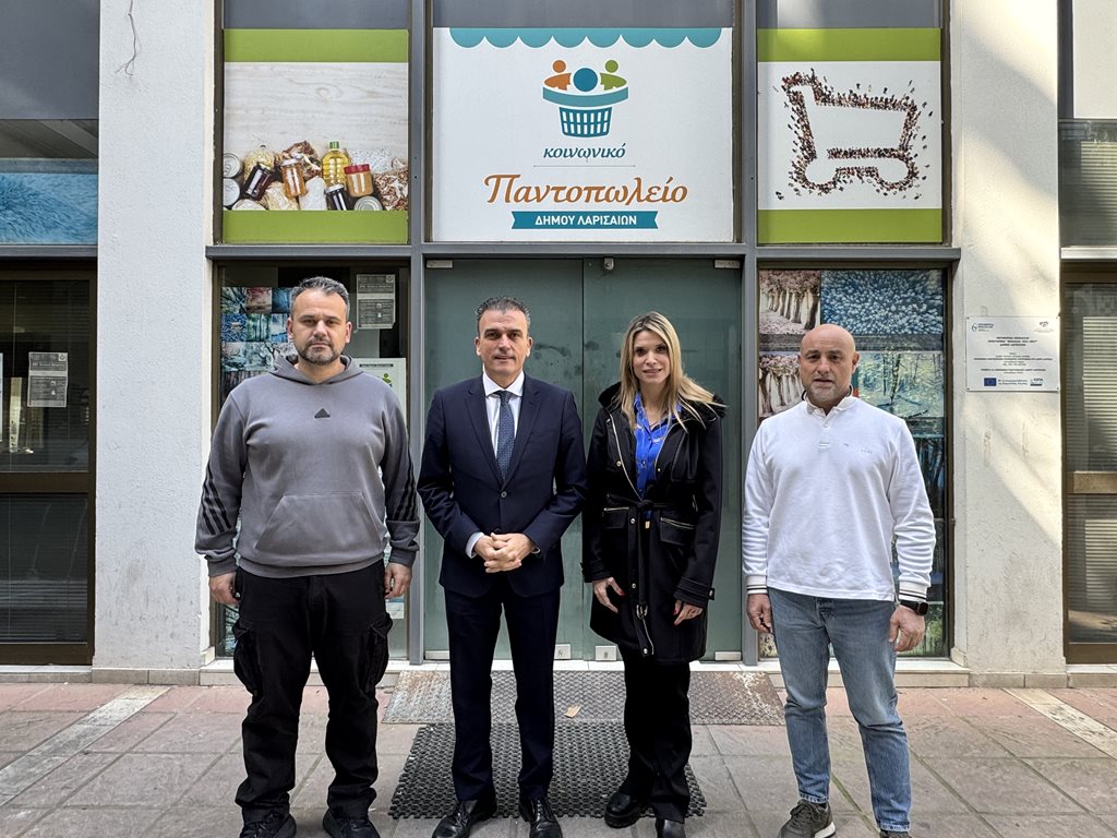 Ομάδα ανθρώπων μπροστά από το Κοινωνικό Παντοπωλείο Λάρισας, υποστηρίζοντας κοινωνικές δράσεις.